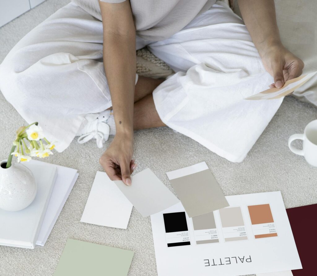 Designer sits on carpet with color palettes and samples, planning creative project.